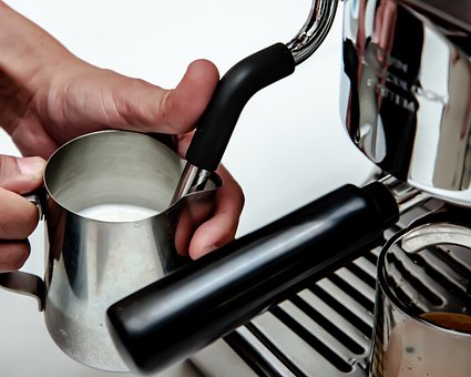 Frothing milk in a milk jug using an espresso machine milk steaming attachment
